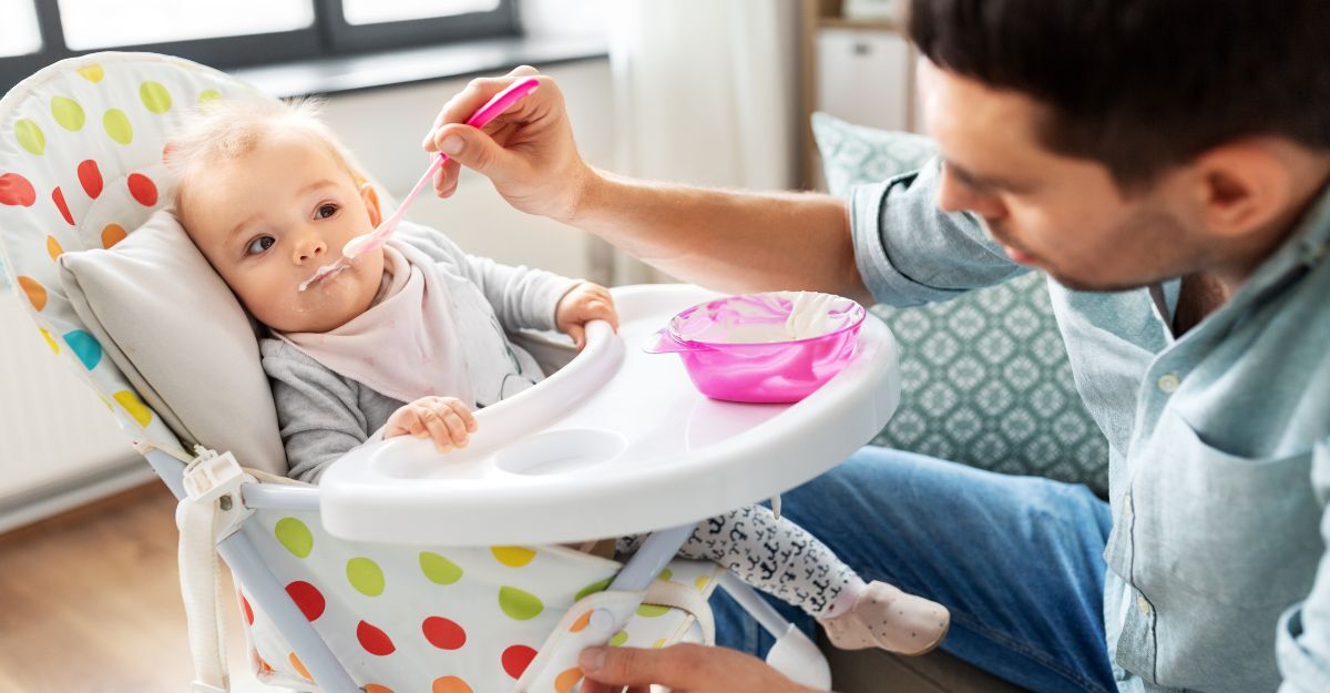 Un uomo imbocca un neonato con un cucchiaino di yogurt per neonati.