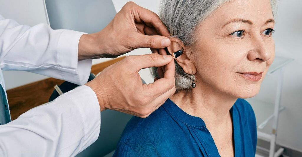 medico inserisce apparecchio acustico ad una signora