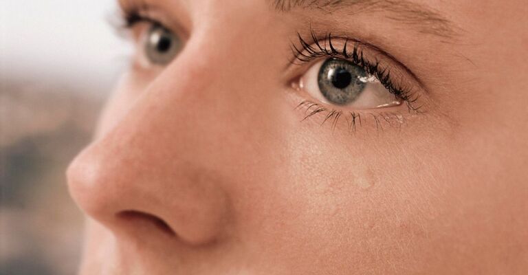 Primo piano del viso di una persona con gli occhi che lacrimano, con una lacrima che le scende lungo la guancia.