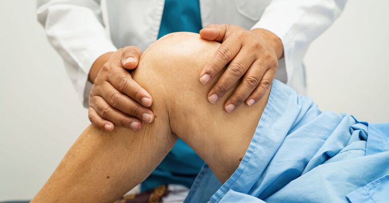 Artrosi del ginocchio e obesità Medico esamina il ginocchio di un paziente, valutando la mobilità articolare durante una visita ortopedica.