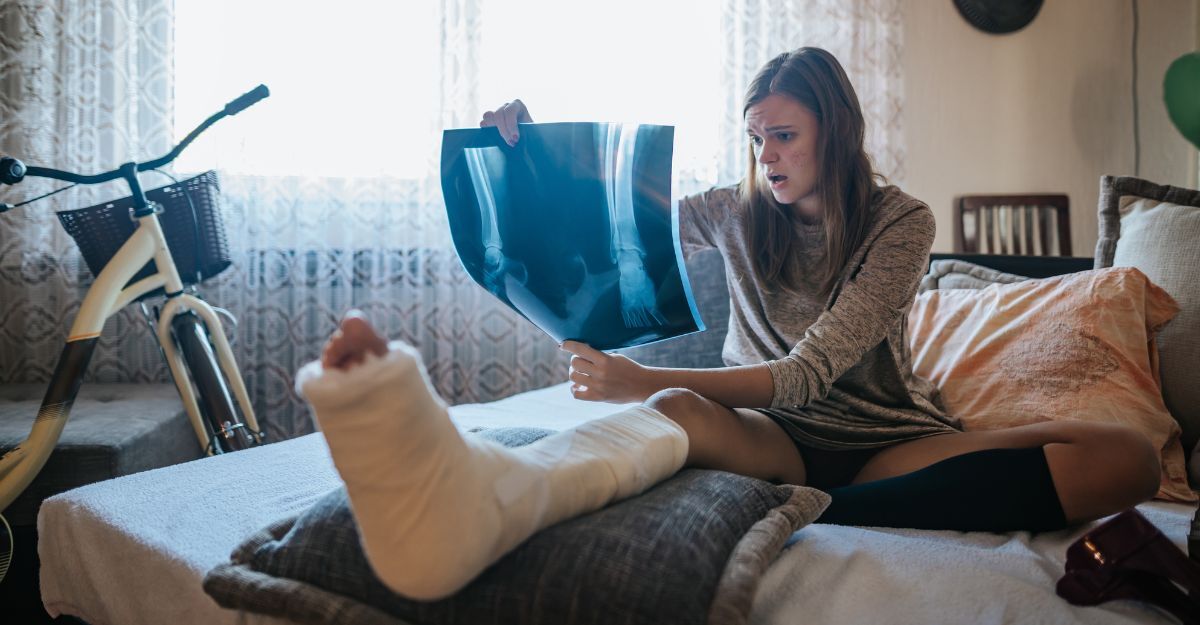 donna sul divano con la gamba rotta, guarda una radiografia