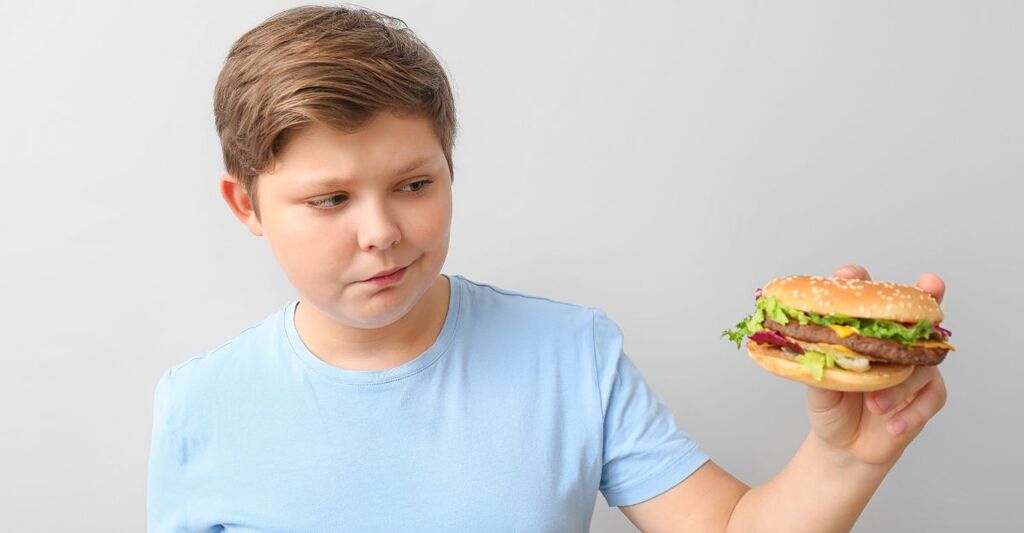Un bambino guarda un panino da fast food.
