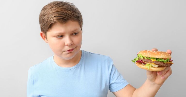Un bambino guarda un panino da fast food.