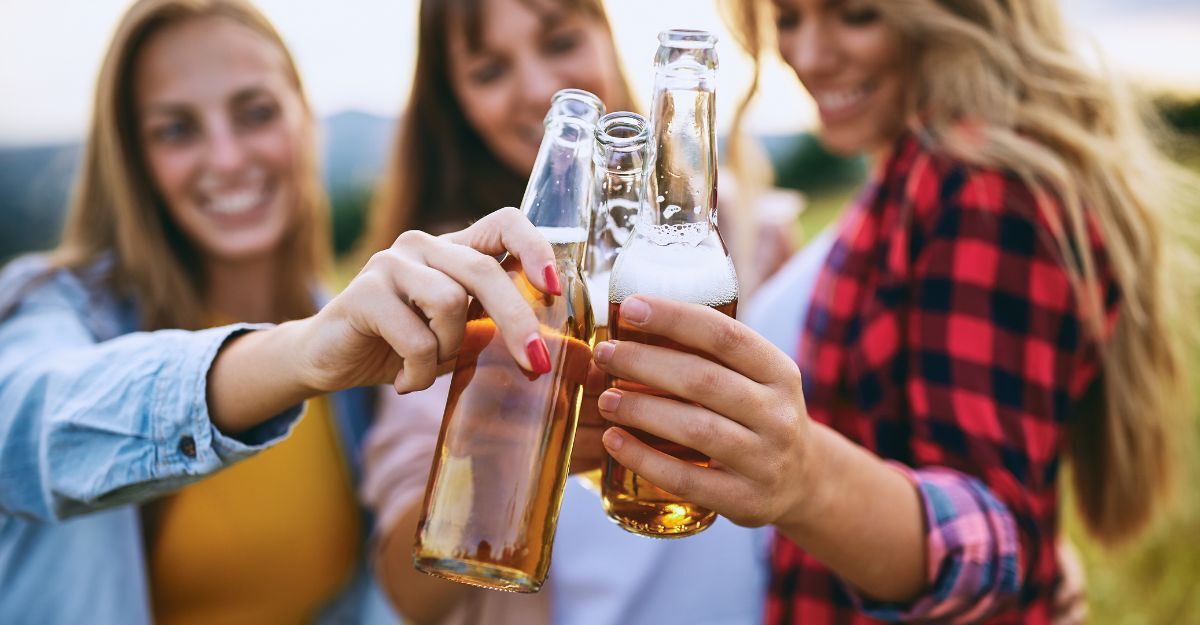 Ragazze brindano con bottiglie di birra all'aperto.