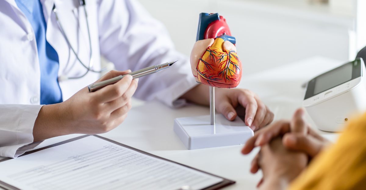 Un paziente parla con un medico davanti ad un modellino di un cuore