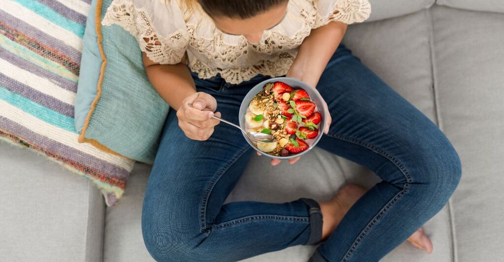 donna mangia insalata sul divano