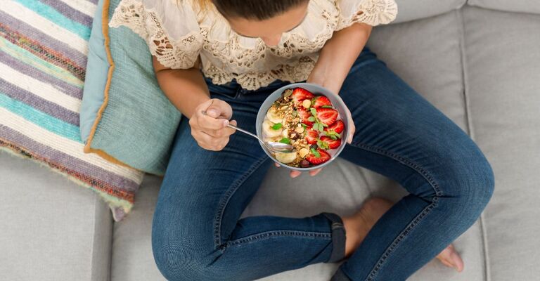 donna mangia insalata sul divano