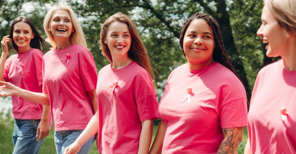 Donne che indossano nastri rosa a sostegno della sensibilizzazione sul cancro al seno mentre camminano nel parco