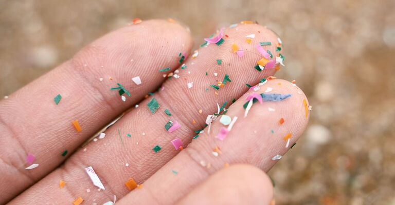 Primo piano laterale di microplastiche depositate sulla mano di una persona. Concetto di inquinamento idrico e riscaldamento globale. Idea del cambiamento climatico