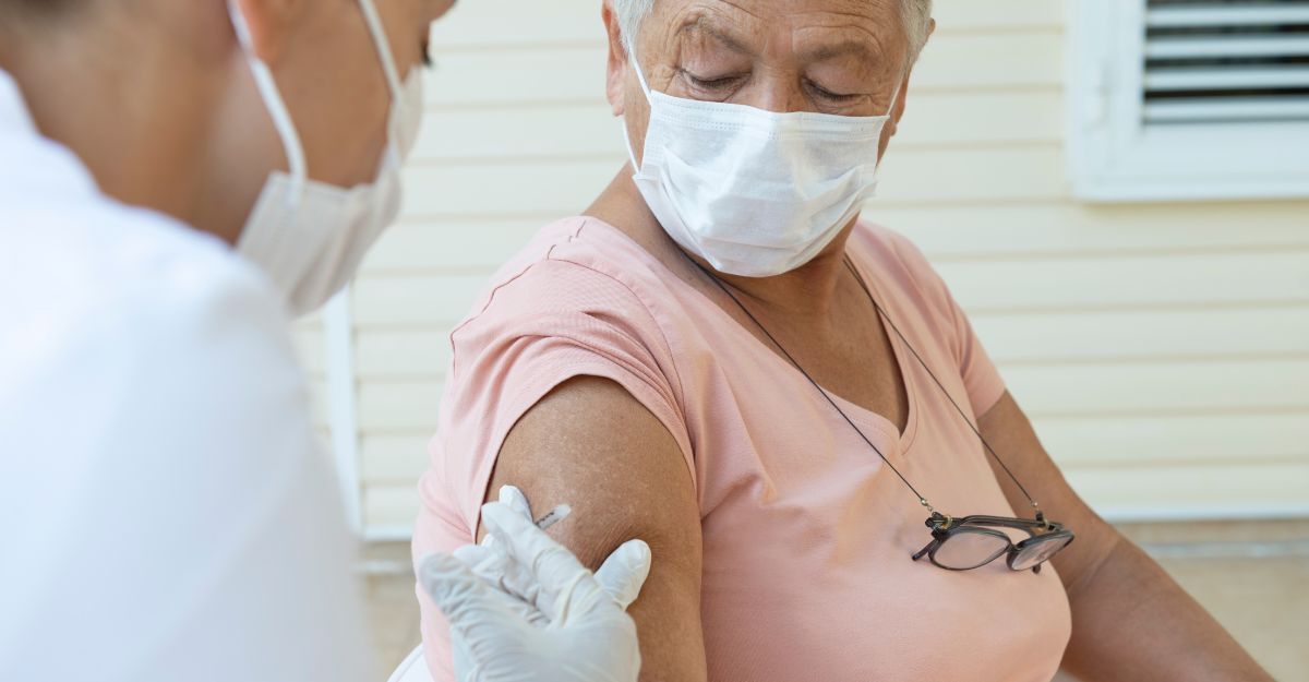 Una infermiera inetta il vaccino a una paziente con la mascherina.