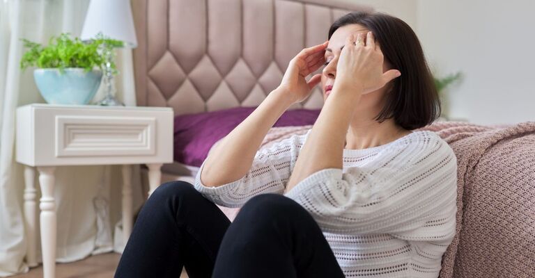 A che età si va in menopausa Ecco sintomi e come riconoscerla donna seduta per terra si tiene la testa