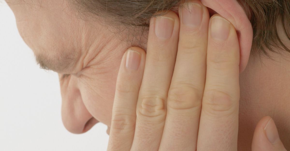 Un uomo con espressione sofferente per dolore all'orecchio.