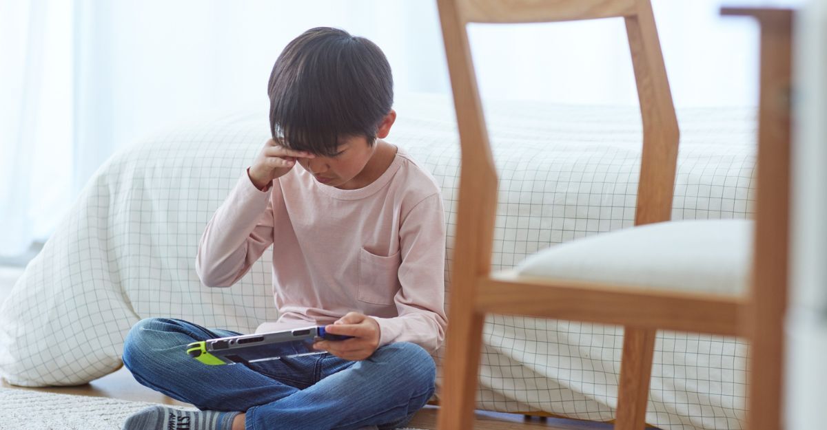 bimbo seduto per terra con un videogioco in mano