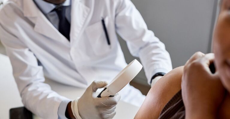 Un dermatologo osserva la pelle di un paziente con uno strumento specifico