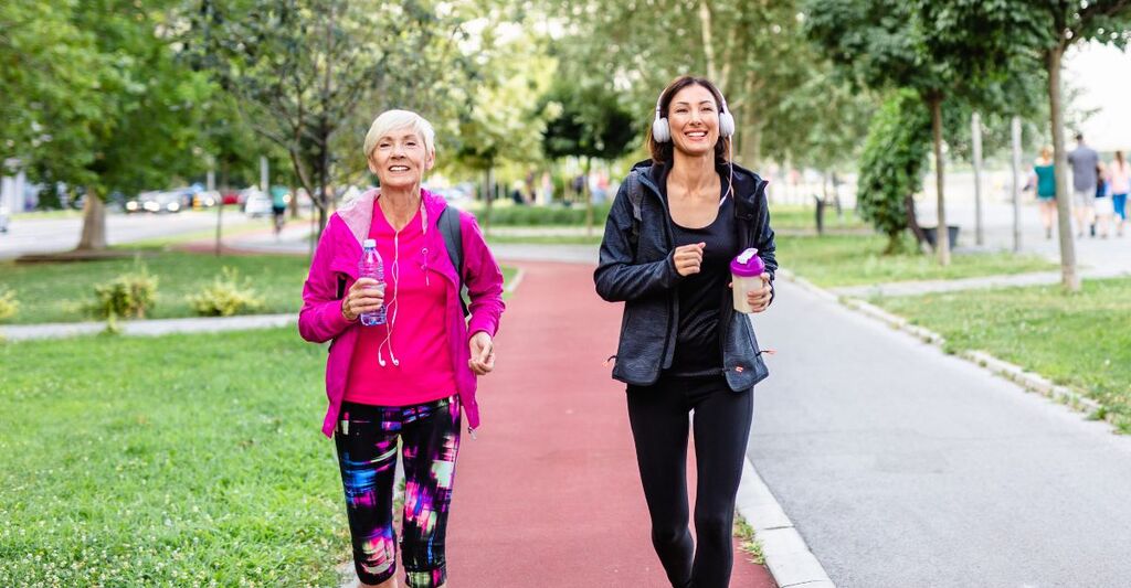 Mamma e figlia una vicino all'altra che camminano sulla pista da jogging