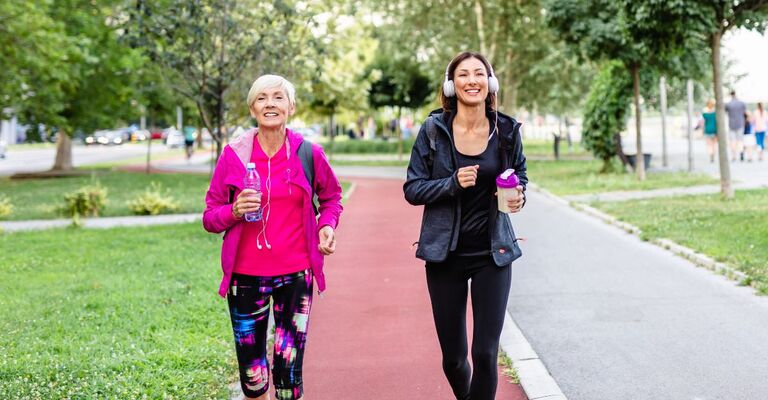 Mamma e figlia una vicino all'altra che camminano sulla pista da jogging