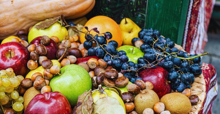 Primo piano di frutta e verdura della stagione autunnale tra cui uva, mele, arance, pere