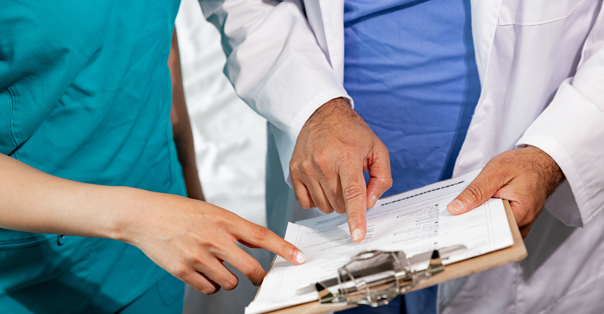 Due professionisti sanitari indicano dei documenti su una cartella clinica.
