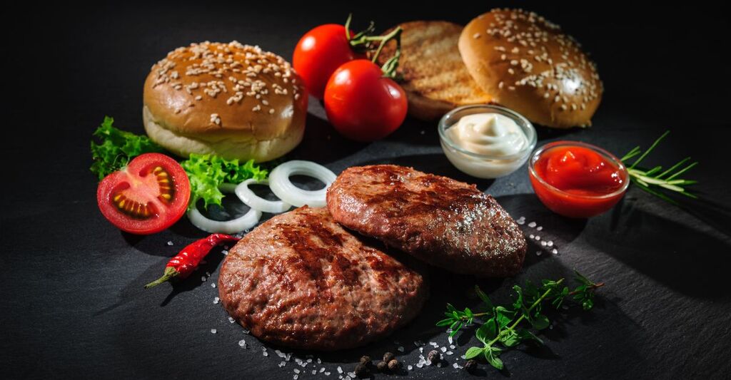 Burger, pomodori e pane su un tavolo.