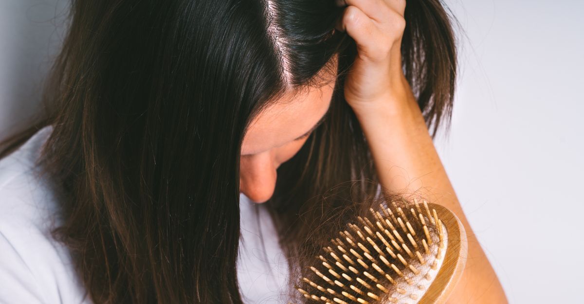 Donna con spazzola piena di capelli caduti.
