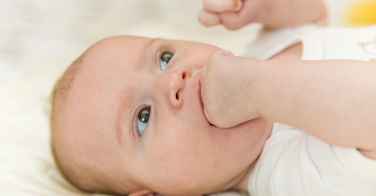 Un neonato che si mette la mano in bocca