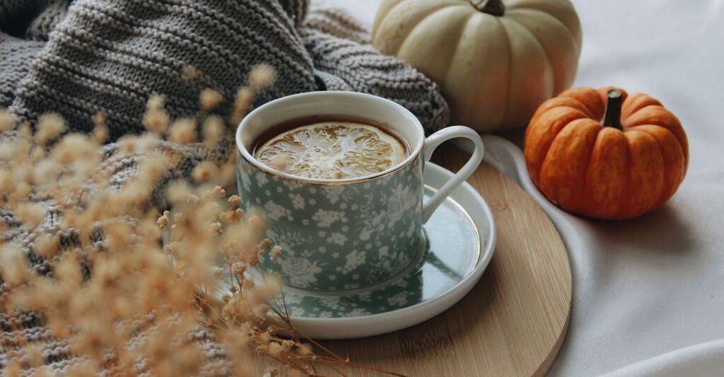 tazza di tisana con 2 zucche arancioni di fianco
