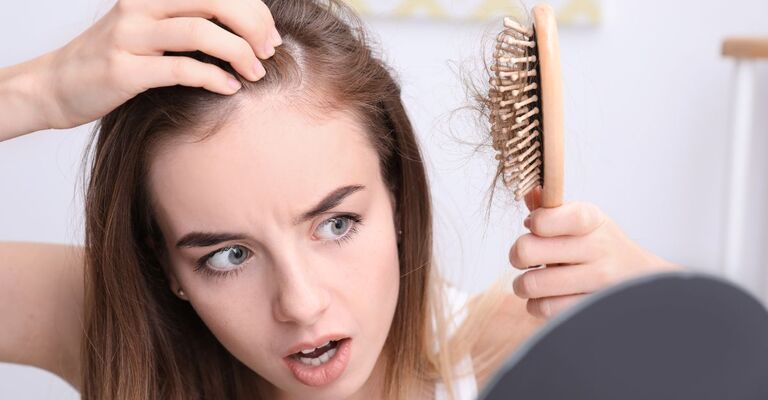 ragazza si pettina e nota perdita di capelli allo specchio