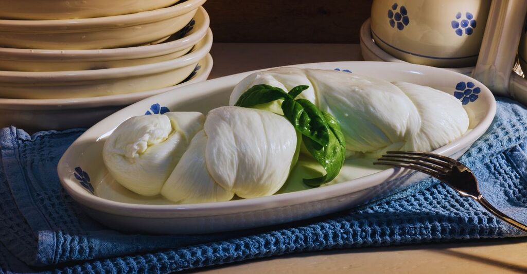 Primo piano della mozzarella con del basilico in un vassoio di ceramica dipinta a mano