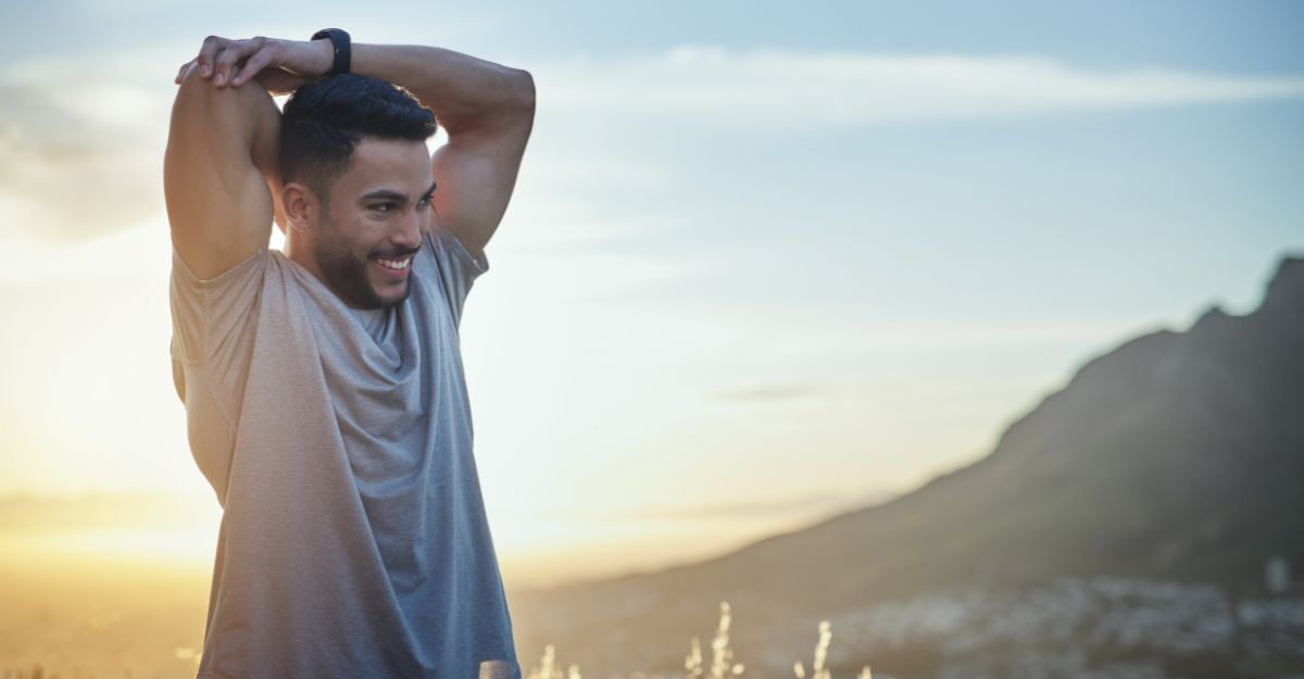 Uomo sorridente che si stira all'aperto al tramonto.