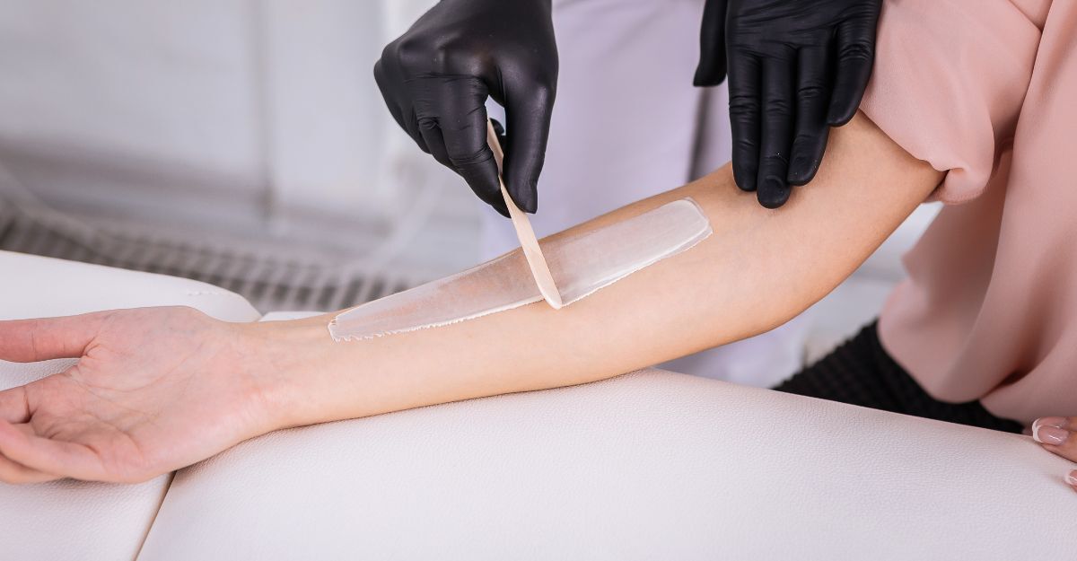 Una estetista applica la crema depilatoria sul braccio di una donna in gravidanza.