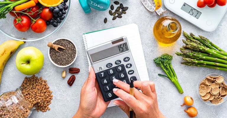 Cibo salutare, calcolatrice e bilancia alimentare su un tavolo.