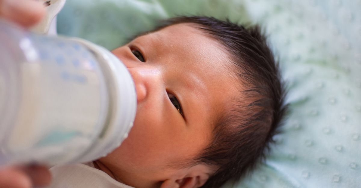 Un neonato che beve il latte dal biberon.