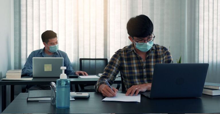 Due uomini in ufficio con mascherina per proteggersi dal Sars-Cov2