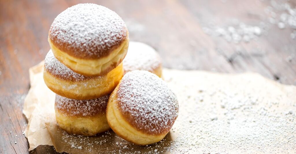 Primo piano di ciambelle (pancake berlinesi) spolverate con zucchero a velo servite su un tavolo di legno rustico