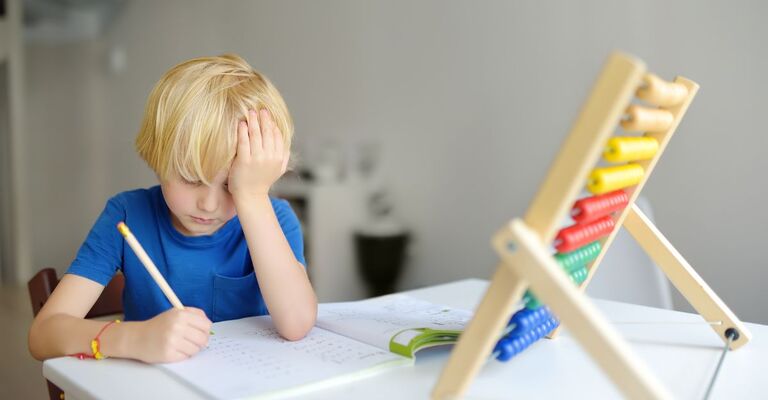 Discalculia bambino fa i compito con un pallottoliere davanti