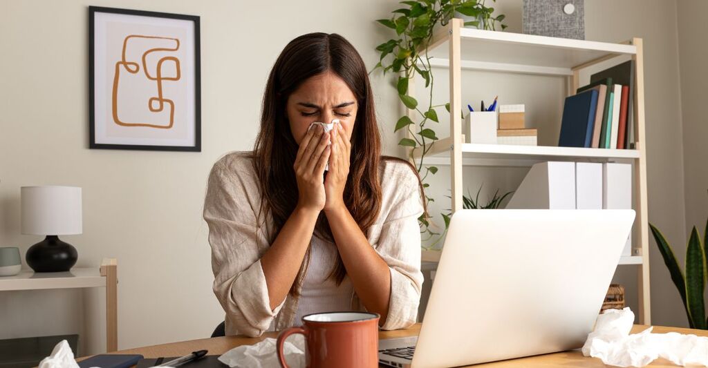 ragazza seduta alla scrivania si soffia il naso
