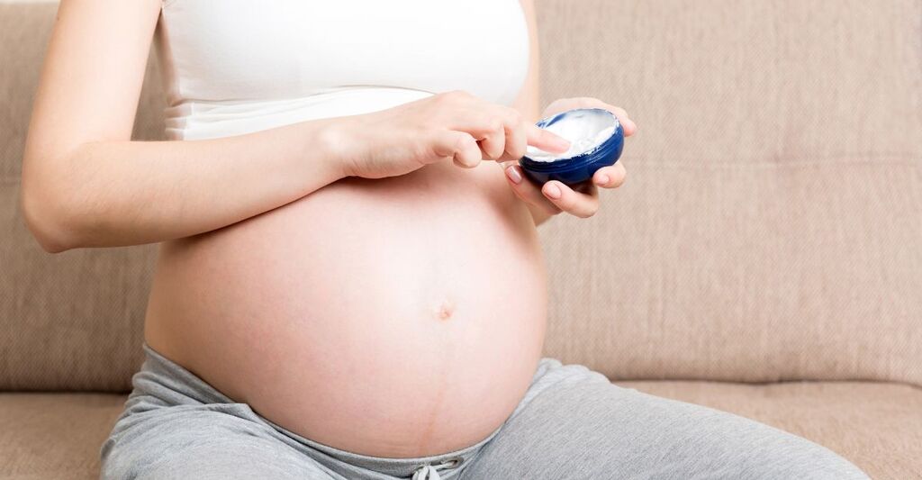 Una donna incinta mette la crema anticellulite.