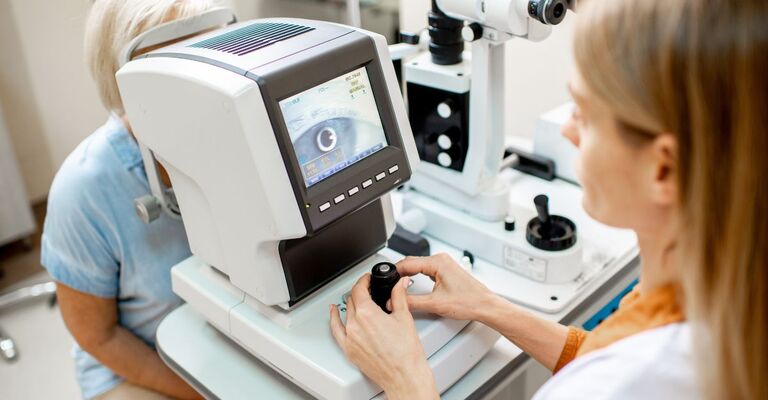Un oculista esamina gli occhi di un paziente anziano utilizzando un microscopio digitale durante una visita medica presso lo studio oculistico