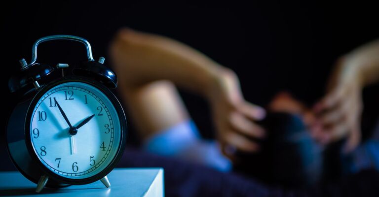 Cambio dell'ora Sveglia e persona che non dorme.