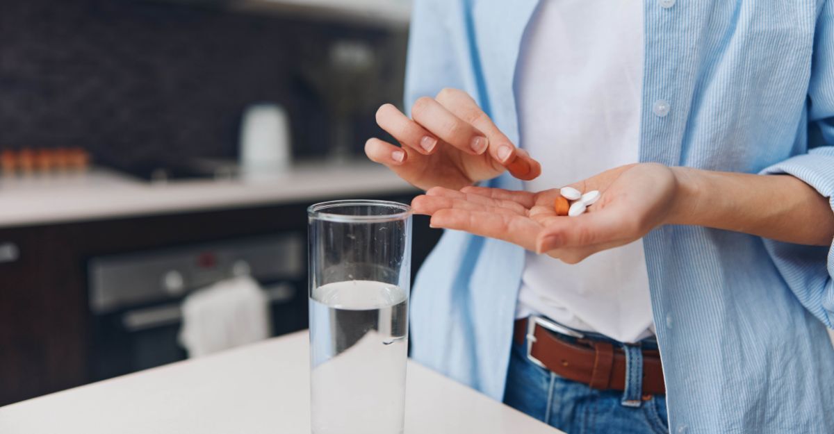 Donna che tiene una pillola in mano e si prepara a prendere il farmaco con un bicchiere d'acqua