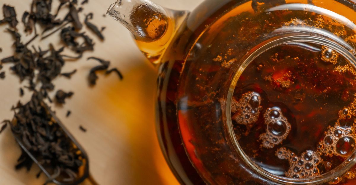 Tè nero o infuso scuro in una teiera di vetro.