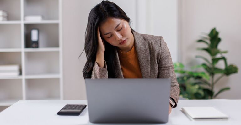 Emicrania: impatto sociale ed economico su 6 milioni di italiani Giovane donna stressata, stanca, stordita, impiegata d'ufficio, donna d'affari asiatica, che si tocca la testa, si sente triste, stanca, ha mal di testa, emicrania o stress, è esausta dopo aver lavorato al computer, ha il burnout