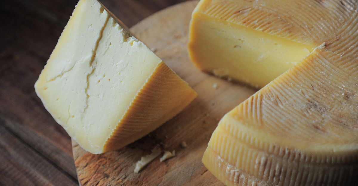 Latte crudo a rischio listeria Formaggio a pasta dura su tagliere di legno.