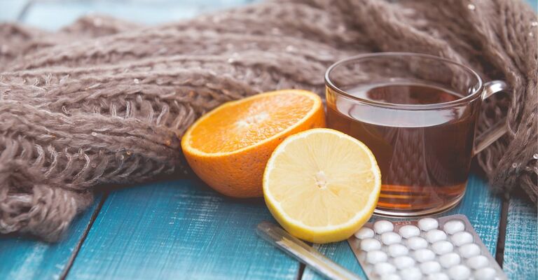 sciarpa di lana, arancia, termometro e pastiglie