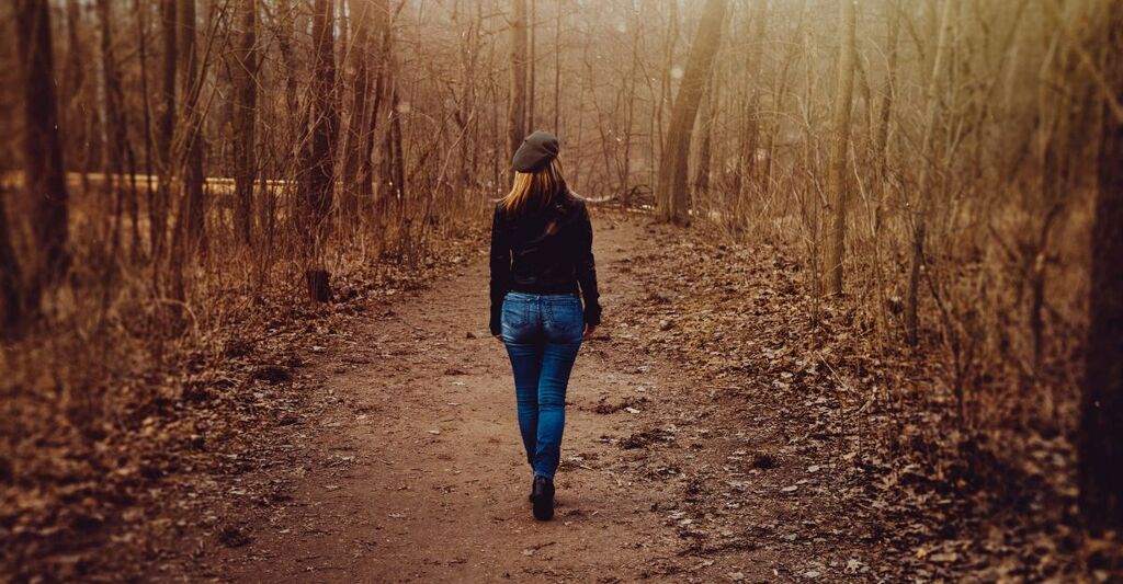 Una donna sensibile al cambio di stagione passeggia in autunno.