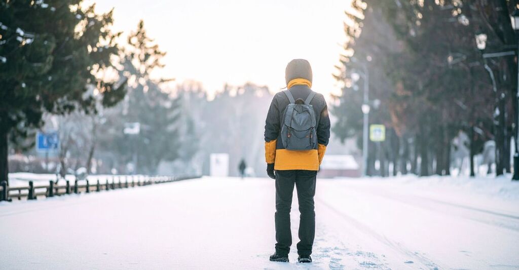 ragazzo di spalle in mezzo ad una strada ghiacciata d'inverno