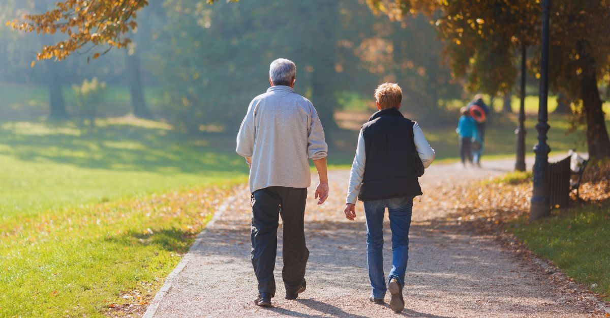 Una coppia di anziani cammina in autunno in un parco con una giornata di sole
