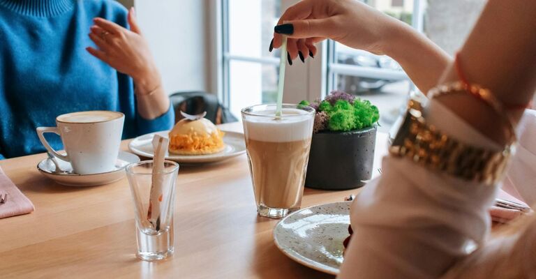 Primo piano di due persone al bar che consumano due bevande calde