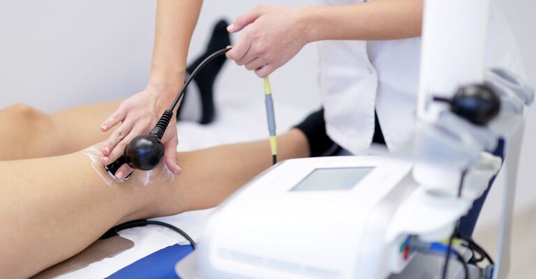 Un medico effettua tecar al ginocchio di un paziente.