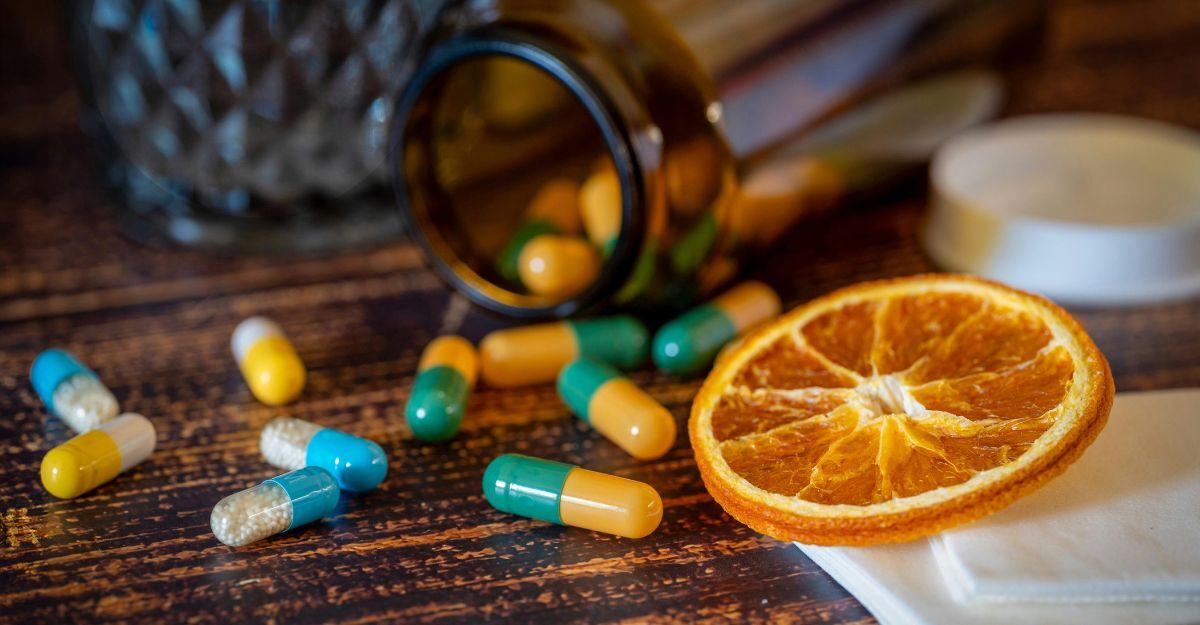 Capsule colorate e una fetta d'arancia su un tavolo di legno.